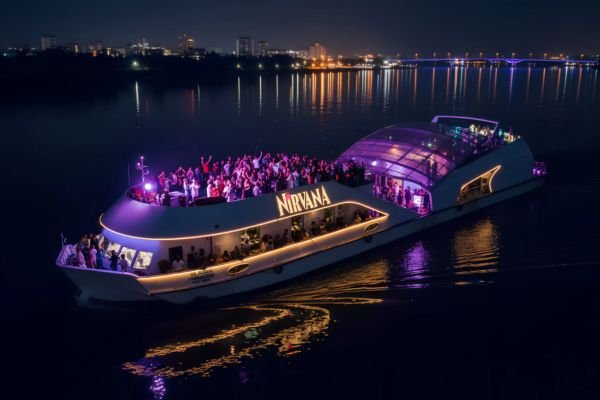 Nirvana cruise party boat lit up at night with guests dancing on the deck